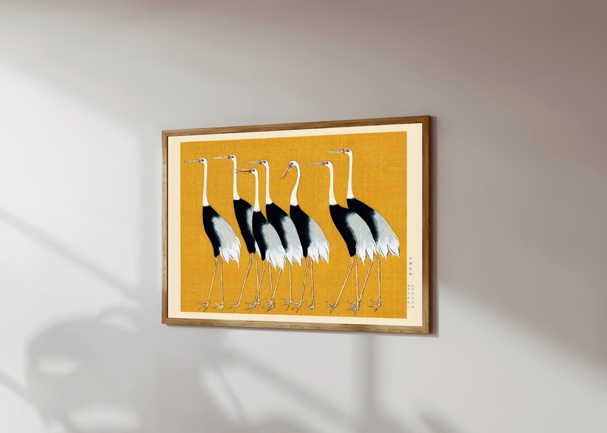 Framed art print of Cranes by Ogata Korin, in a light wood frame on a sunlit white wall, seen at a slight angle
