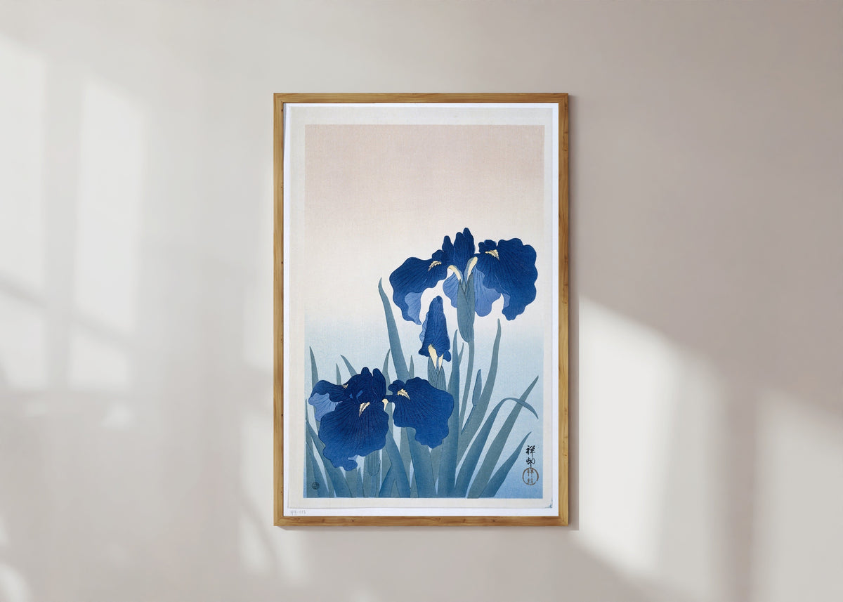 Framed art print of Irises in Blue by Ohara Koson, in a light wood frame on a sunlit white wall