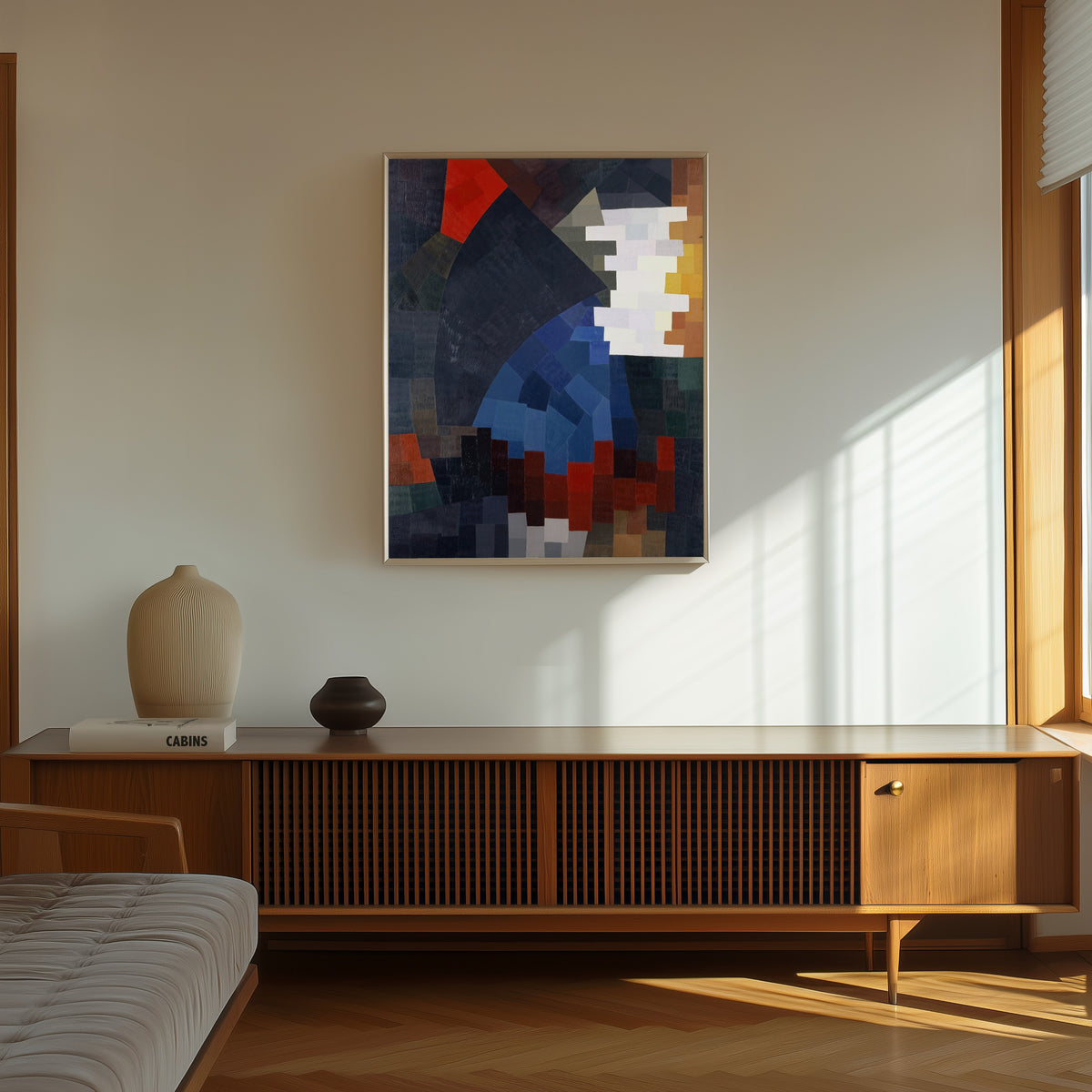 Framed art print of Composition (1932) by Otto Freundlich, in a thin light frame on a sunlit wall above a wooden sideboard
