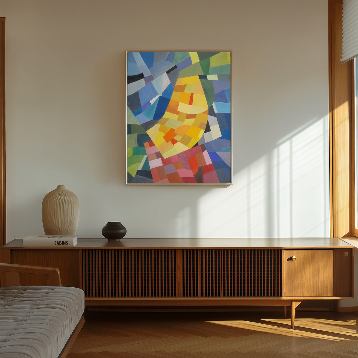Framed art print of Komposition (1930) by Otto Freundlich, in a thin light frame on a sunlit wall above a wooden sideboard