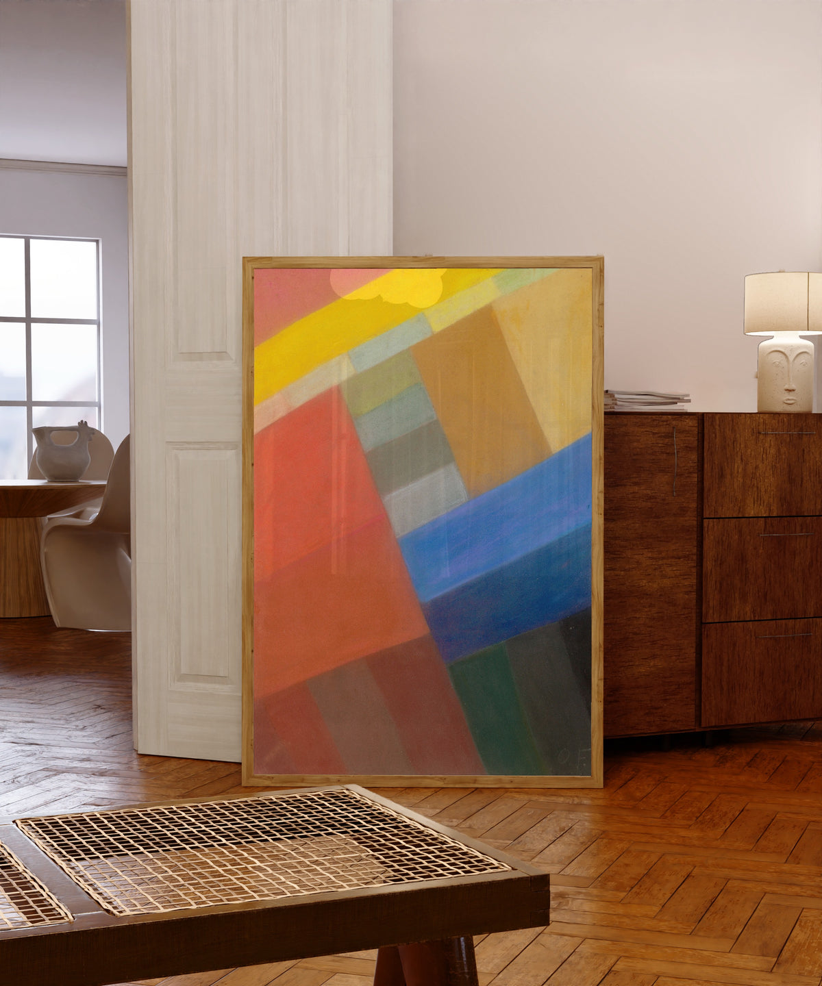 Framed art print of Komposition (c. 1931) by Otto Freundlich, in a light wood frame leaning in a warm room with a parquet floor