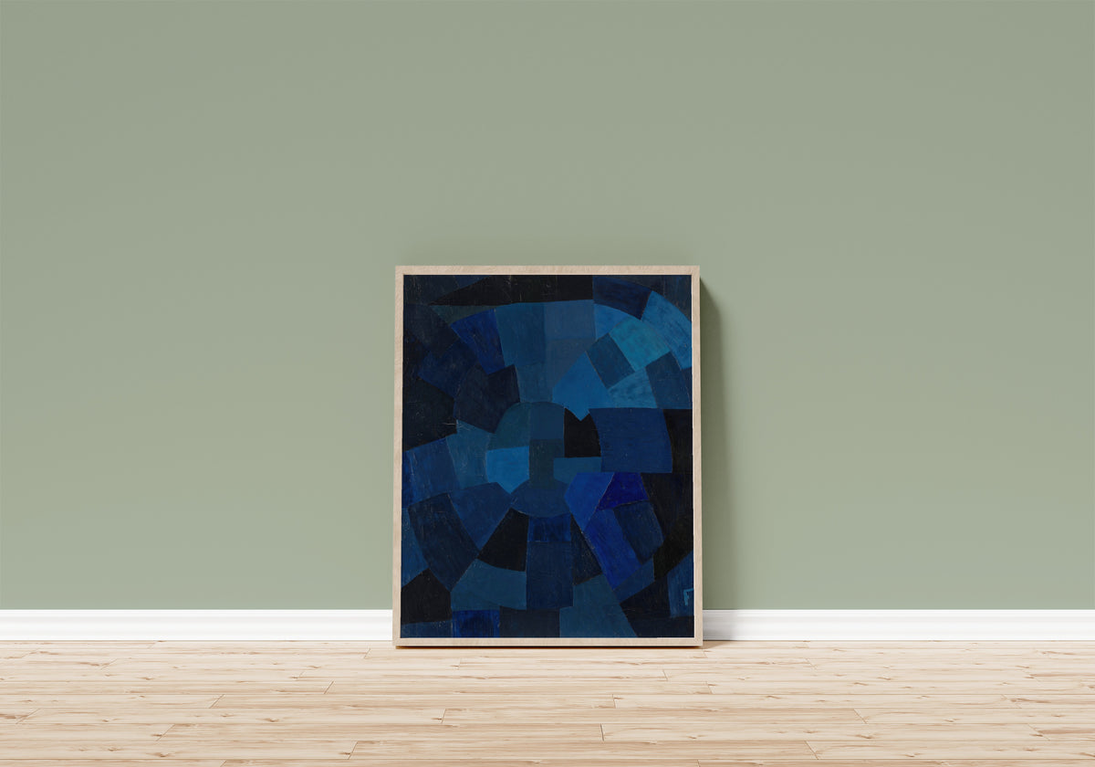 Framed art print of Komposition in Blau (1931) by Otto Freundlich, in a light wood frame leaning on a sage green wall above a wooden floor