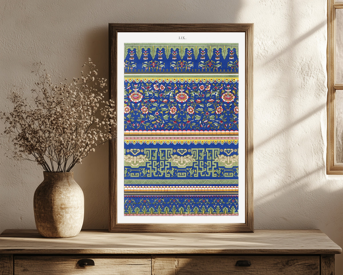 Framed art print of Example of Chinese Ornament Pl.53 (1867) by Owen Jones, in a dark wood frame leaning on a rustic console beside dried flowers