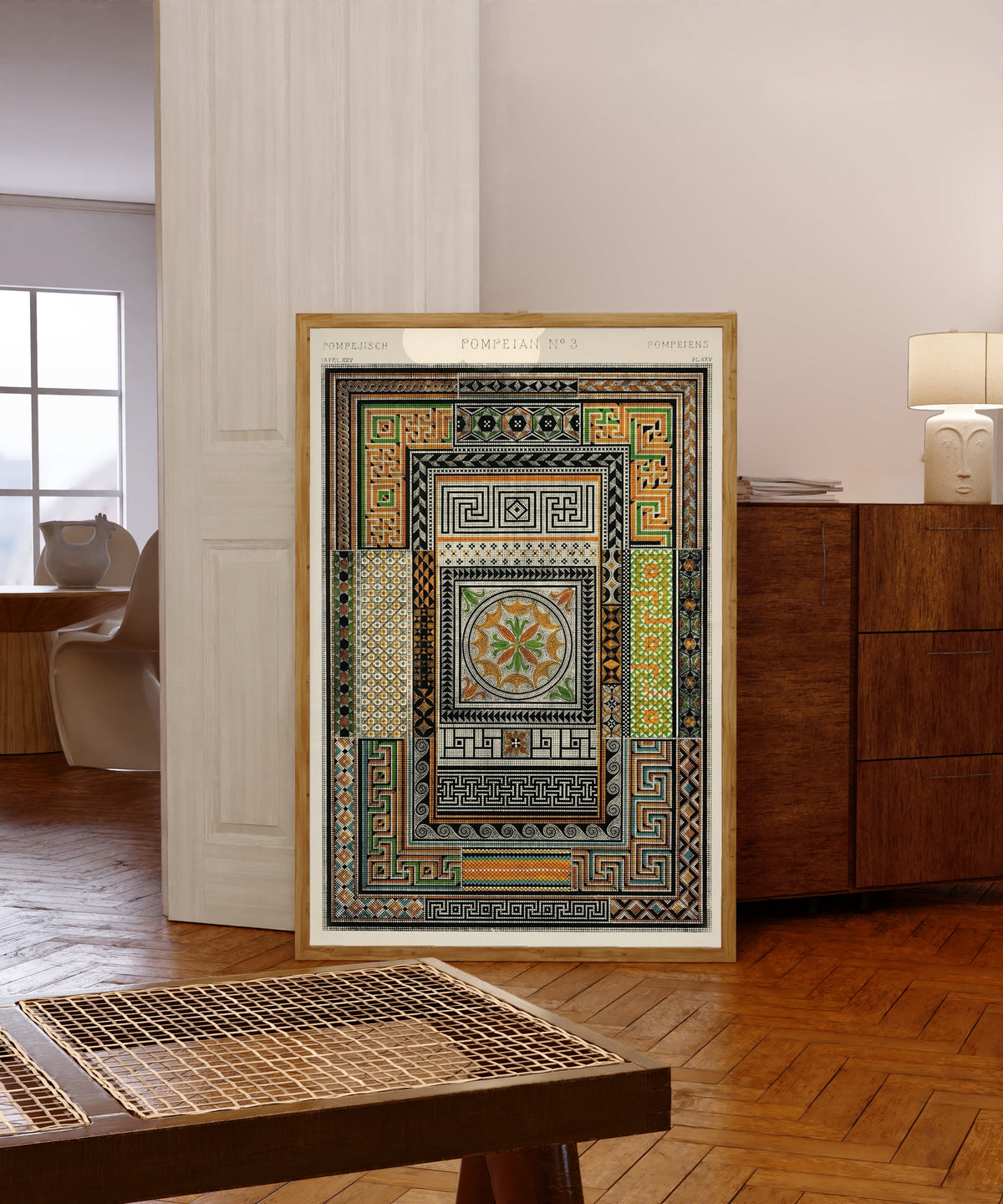 Framed art print of Pompeian by Owen Jones, in a light wood frame leaning in a warm room with a parquet floor