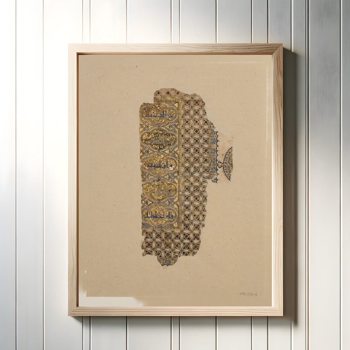 Framed art print of Fragment of a Folio from a Qur'an Manuscript by Muhammad al-Zanjani, in a light wood frame on a white panelled wall
