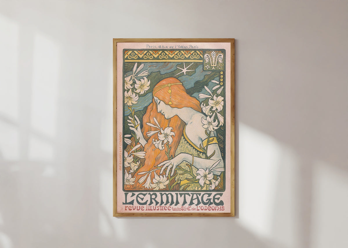 Framed art print of L'Ermitage by Paul Berthon, in a light wood frame on a sunlit white wall
