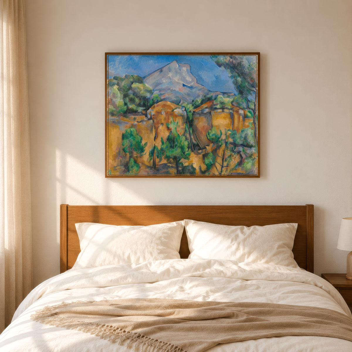 Framed art print of Mont Sainte-Victoire Seen from the Bibémus Quarry by Paul Cezanne, in a slim wood frame above a bed in a sunlit bedroom
