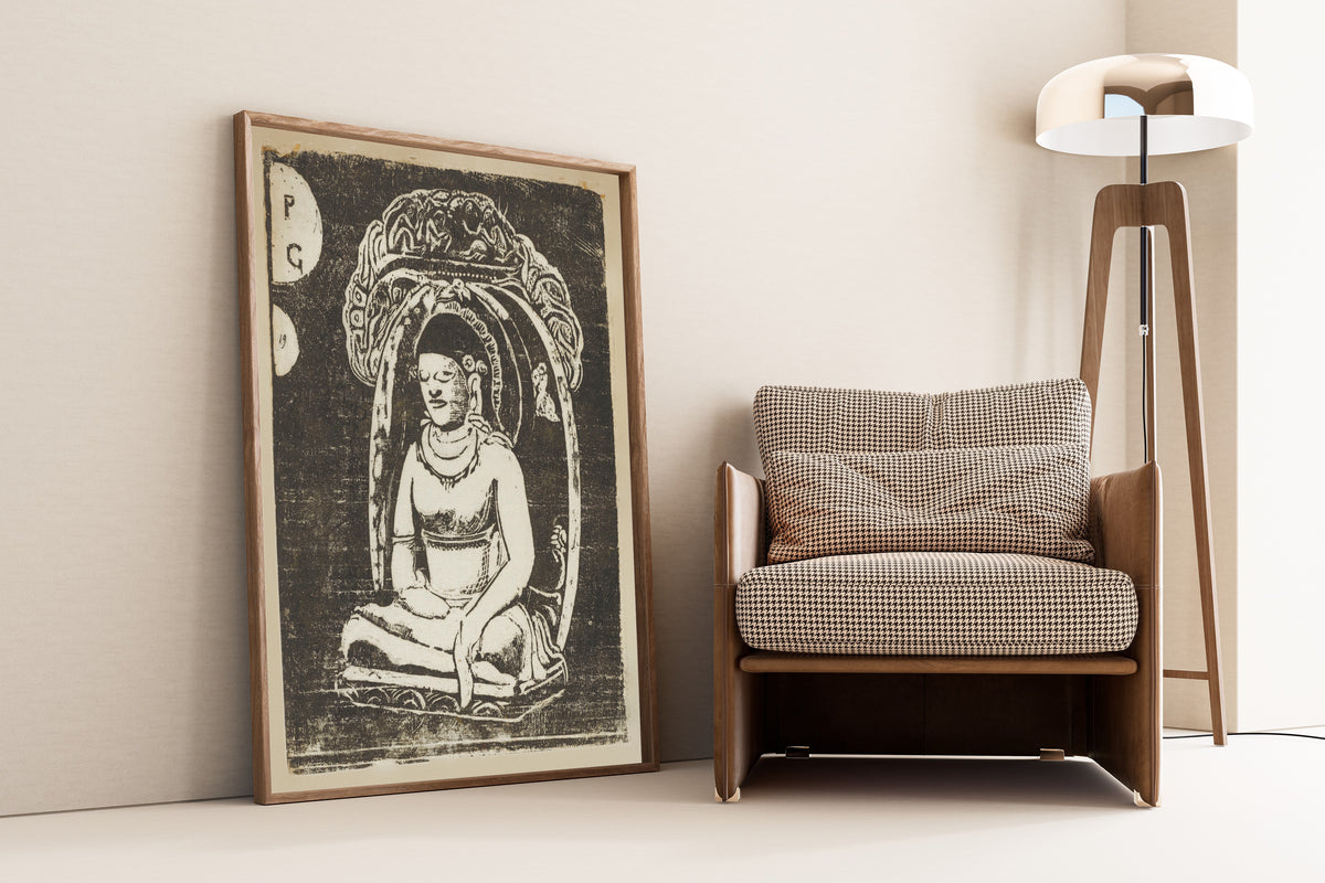 Framed art print of Buddha by Paul Gauguin, leaning against a wall beside an armchair and a floor lamp
