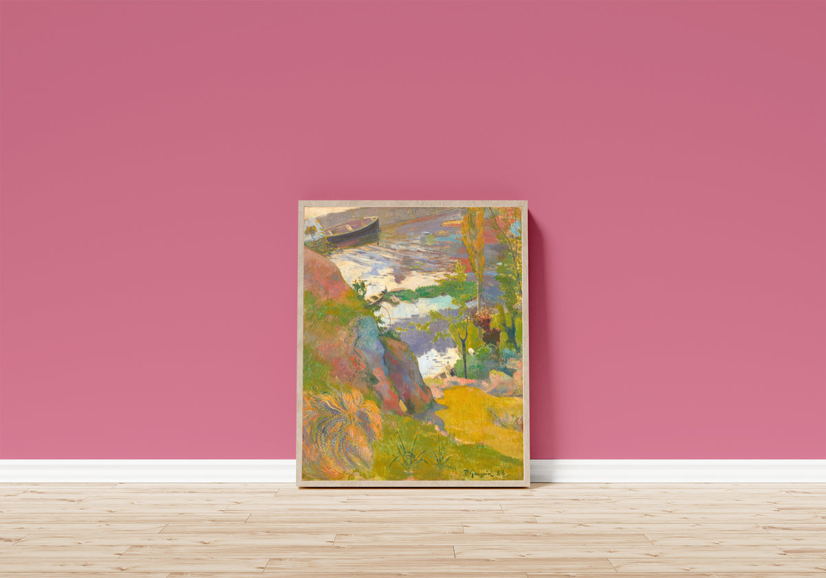 Framed art print of Fisherman and Bathers on the Aven by Paul Gauguin, in a light wood frame leaning on a pink wall above a wooden floor