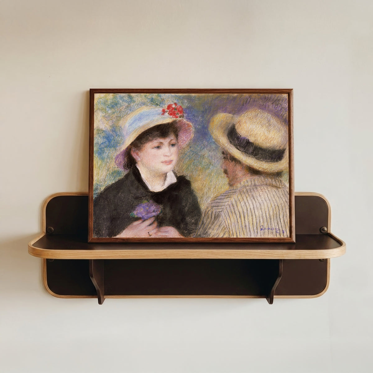 Framed art print of Boating Couple (said to be Aline Charigot and Renoir) by Pierre-Auguste Renoir, in a dark wood frame resting on a wall shelf