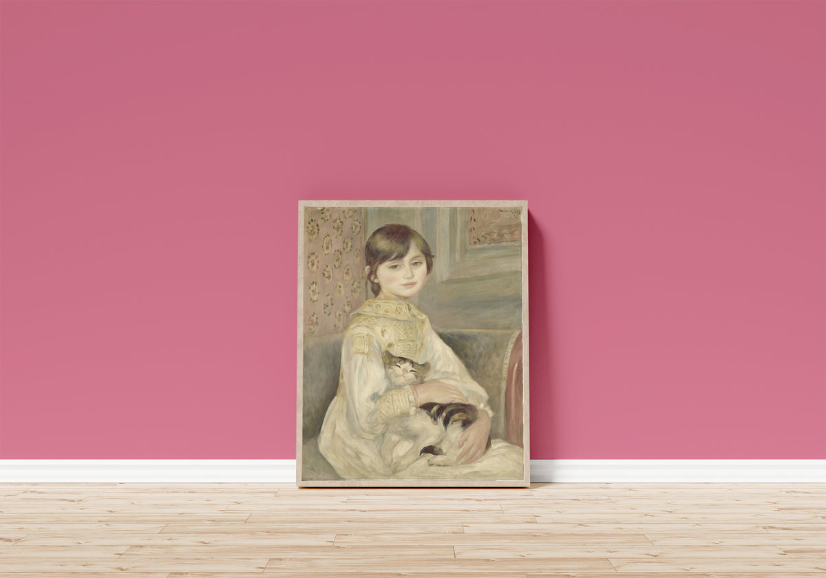 Framed art print of Julie Manet by Pierre-Auguste Renoir, in a light wood frame leaning on a pink wall above a wooden floor