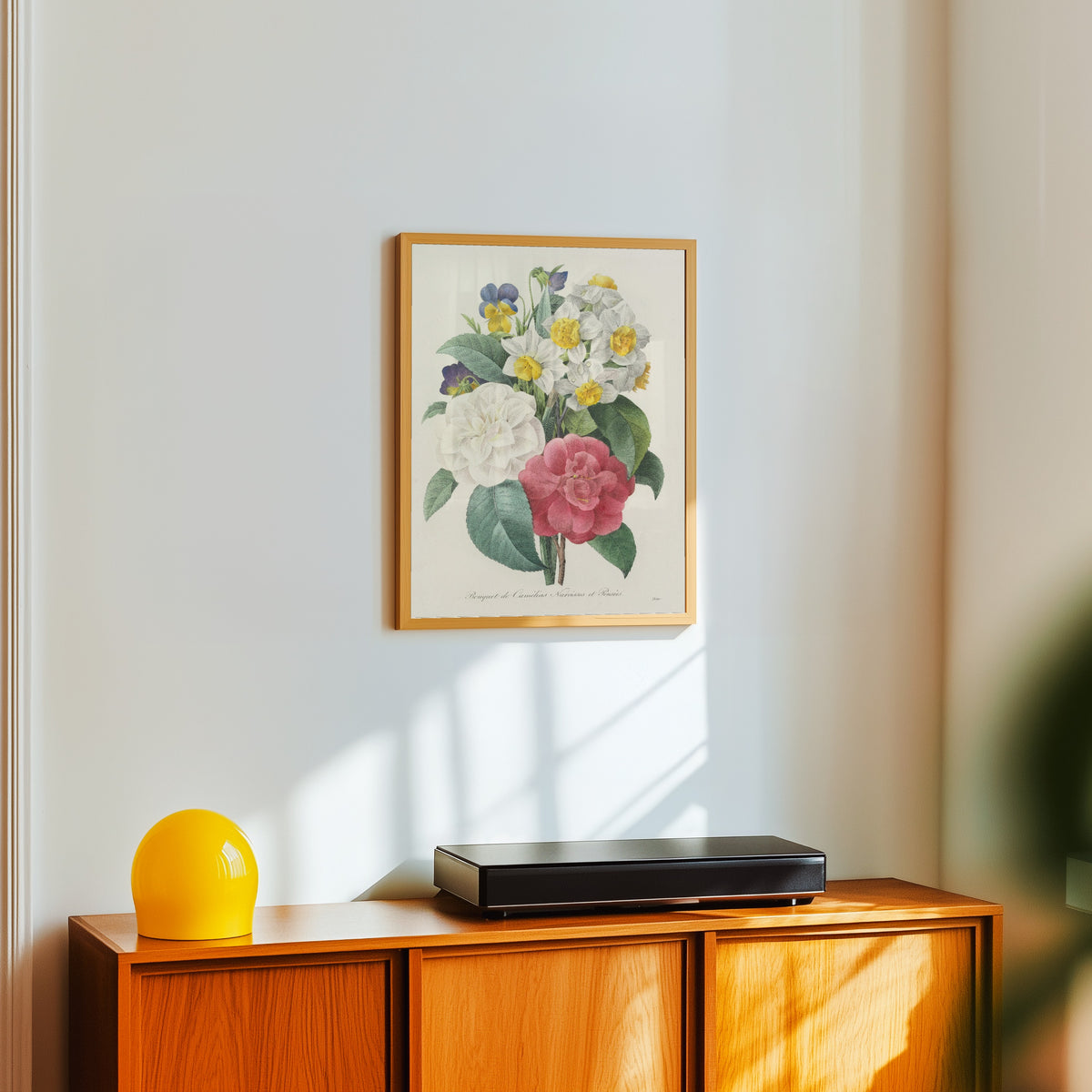 Framed art print of Choix des plus belles fleurs: Bouquet of… by Pierre-Joseph Redouté, in a light wood frame on a white wall above an orange sideboard