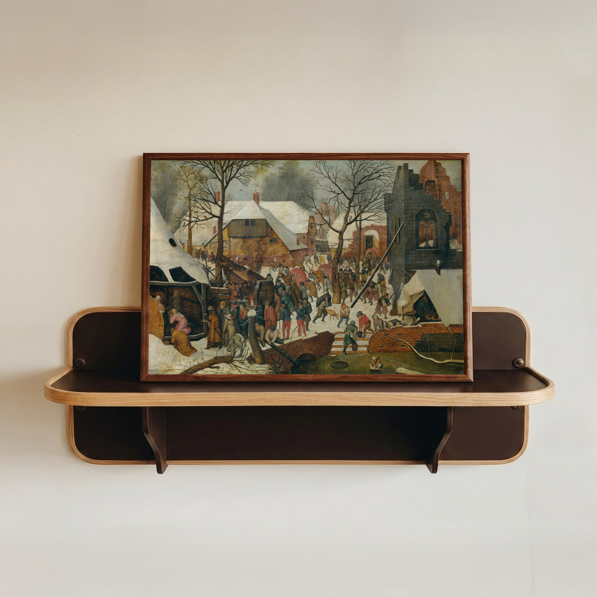 Framed art print of The Adoration of the Magi in the Snow by Pieter Brueghel the Younger, in a dark wood frame resting on a wall shelf