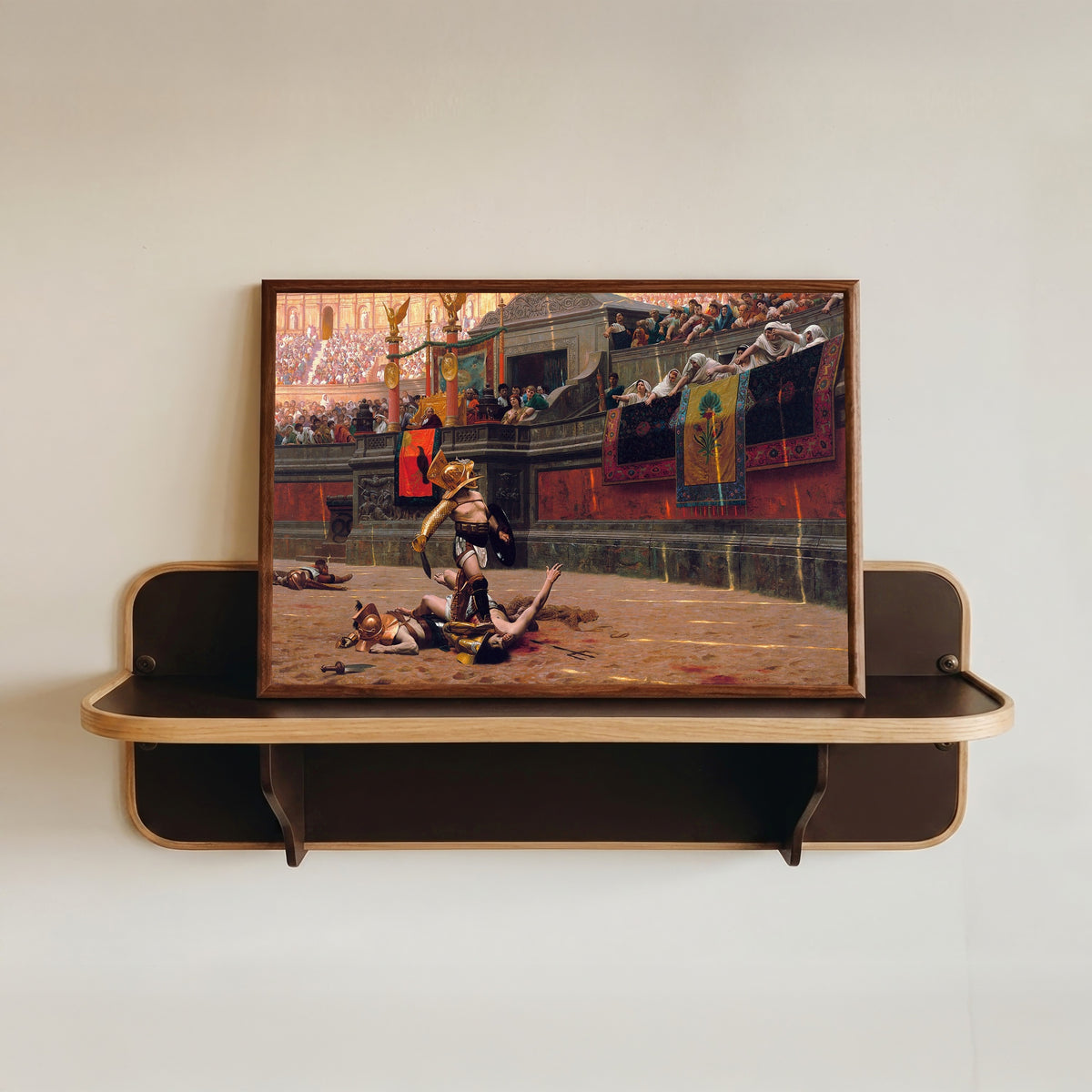 Framed art print of Pollice Verso by Jean-Léon Gérôme, in a dark wood frame resting on a wall shelf
