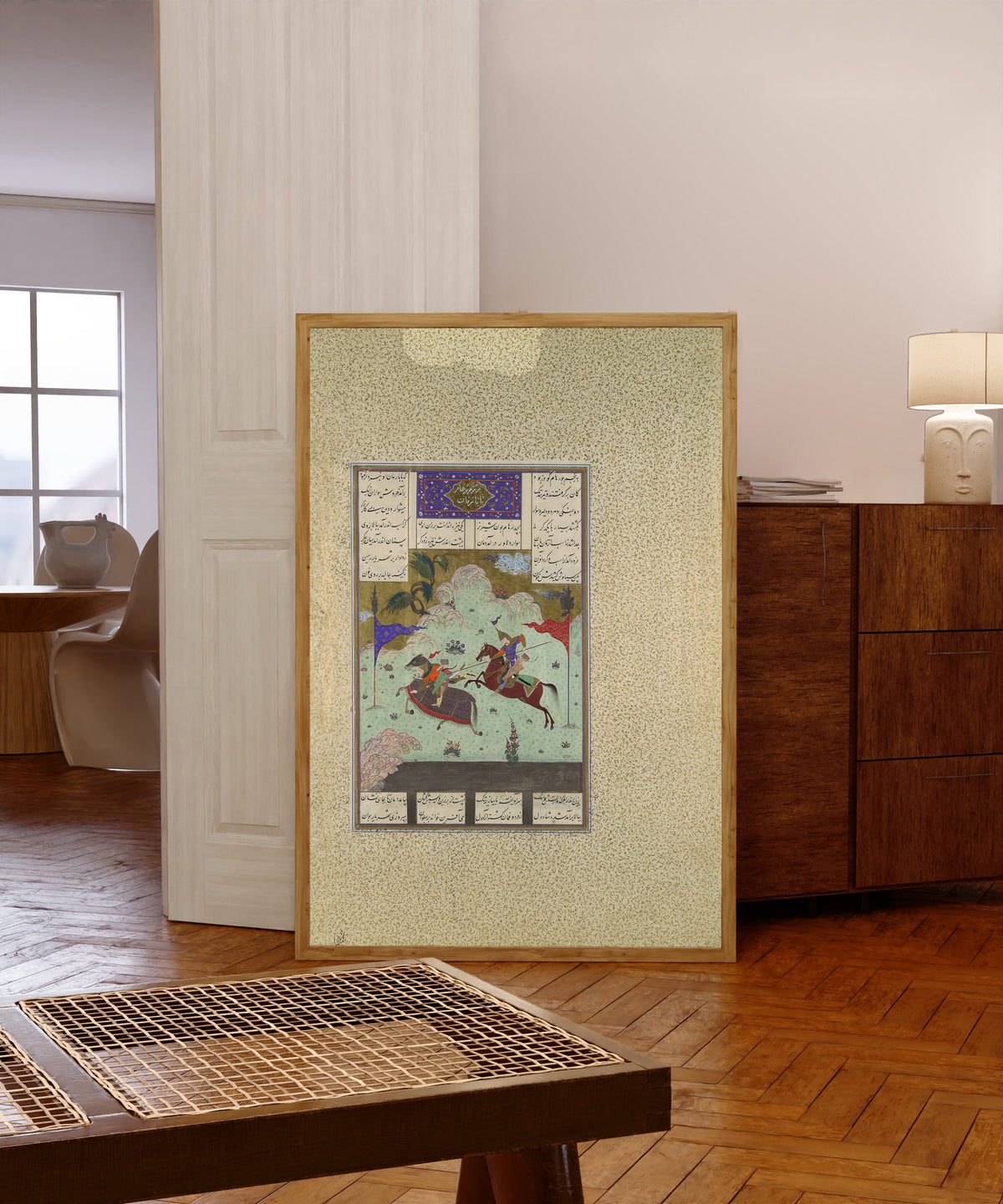 Framed art print of Shahnama of Shah Tahmasp: The Fifth Joust… by Qasim ibn Ali (attributed), in a light wood frame leaning in a warm room with a parquet floor