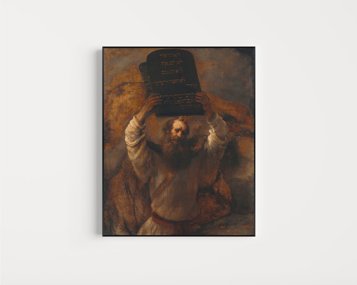 Framed art print of Moses with the Tablets of the Law by Rembrandt van Rijn, in a slim black frame on a plain white wall