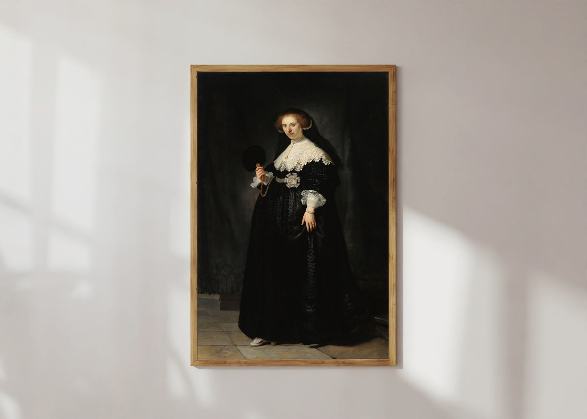 Framed art print of Portrait of Oopjen Coppit by Rembrandt van Rijn, in a light wood frame on a sunlit white wall