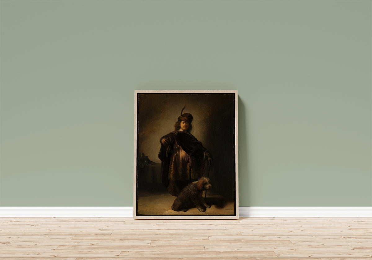 Framed art print of Portrait of the Artist in Oriental Costume by Rembrandt van Rijn, in a light wood frame leaning on a sage green wall above a wooden floor