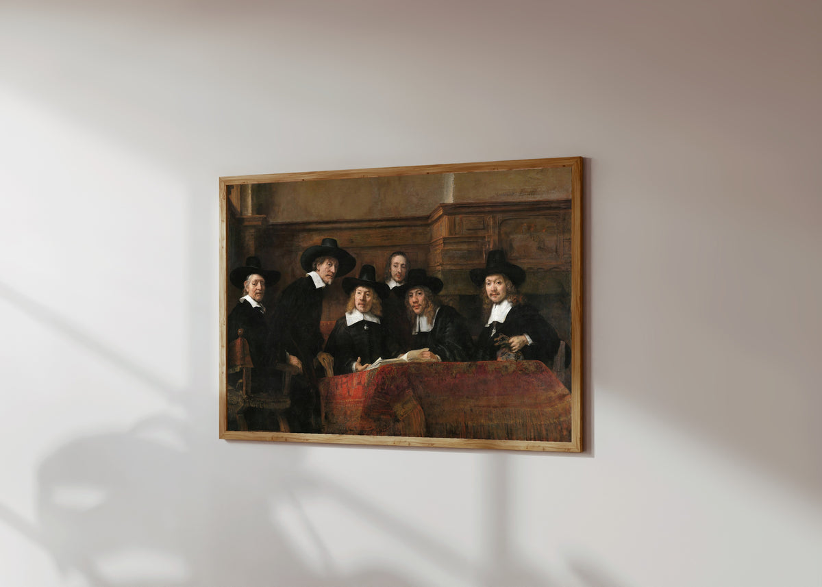 Framed art print of The Sampling Officials of the Amsterdam… by Rembrandt van Rijn, in a light wood frame on a sunlit white wall, seen at a slight angle