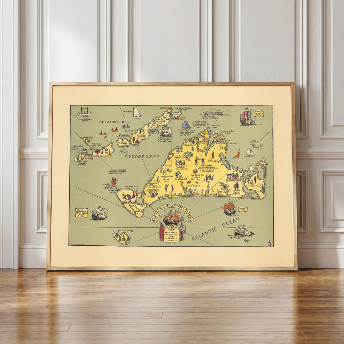 Framed art print of Pictorial Tercentenary Map of Martha's Vineyard and… by Reynold's Printing Co., in a light wood frame leaning against a panelled white wall