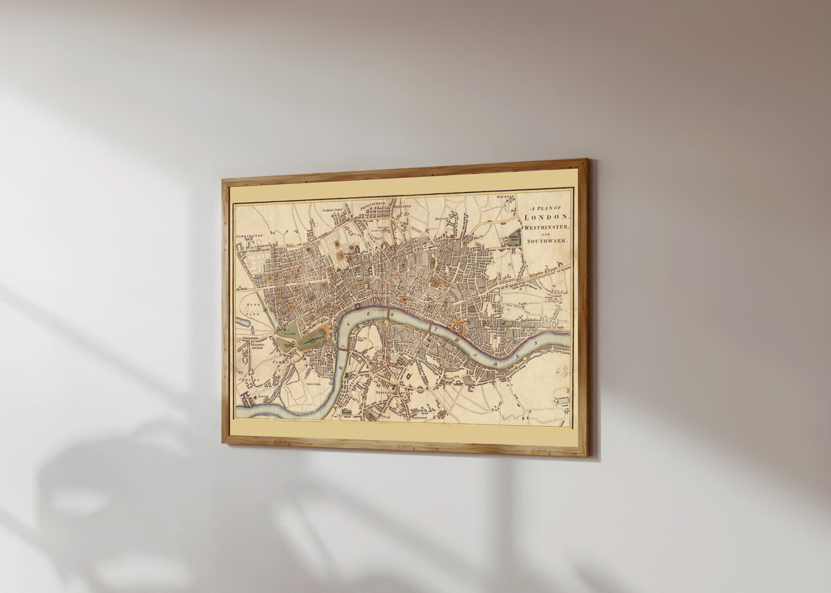 Framed art print of A Plan of London, Westminster and Southwark by Richard Phillips, in a light wood frame on a sunlit white wall, seen at a slight angle