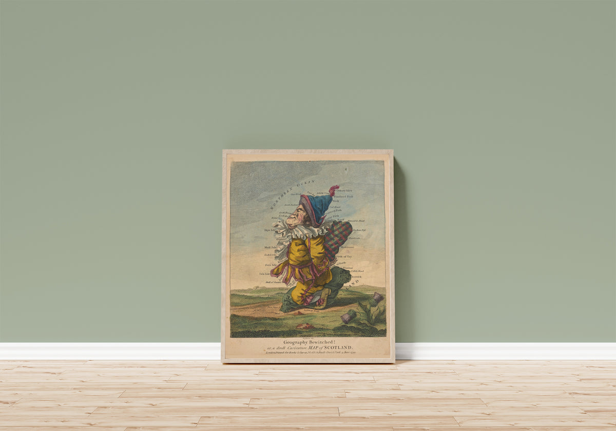 Framed art print of Geography Bewitched! Or, a Droll Caricature Map… by Robert Dighton, in a light wood frame leaning on a sage green wall above a wooden floor
