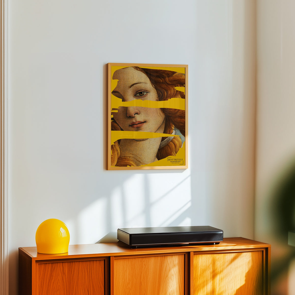Framed art print of The Birth of Venus (Detail) by Sandro Botticelli, in a light wood frame on a white wall above an orange sideboard