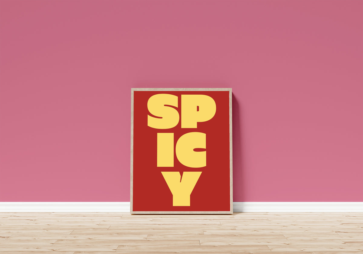 Framed art print of Spicy by Bauhaus, in a light wood frame leaning on a pink wall above a wooden floor