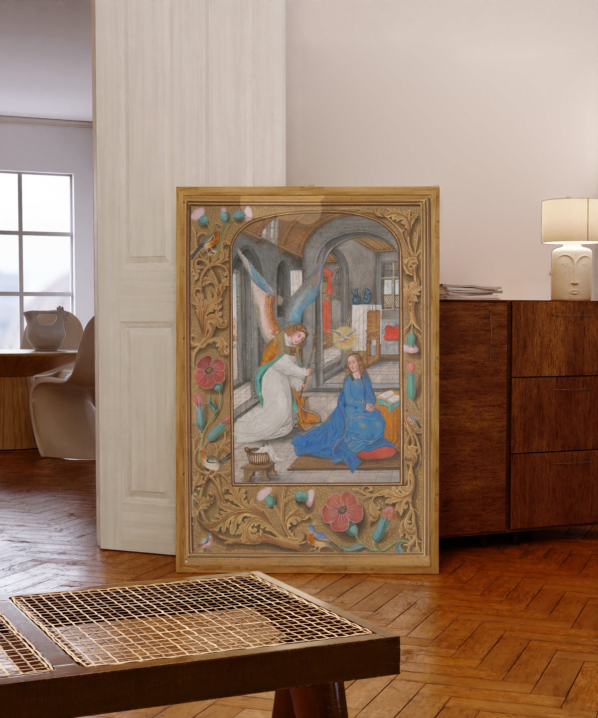 Framed art print of The Annunciation (Grey Stone Room), in a light wood frame leaning in a warm room with a parquet floor