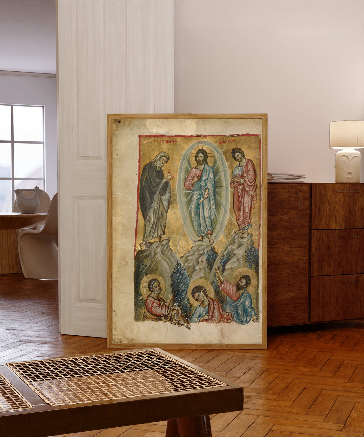 Framed art print of The Transfiguration, in a light wood frame leaning in a warm room with a parquet floor