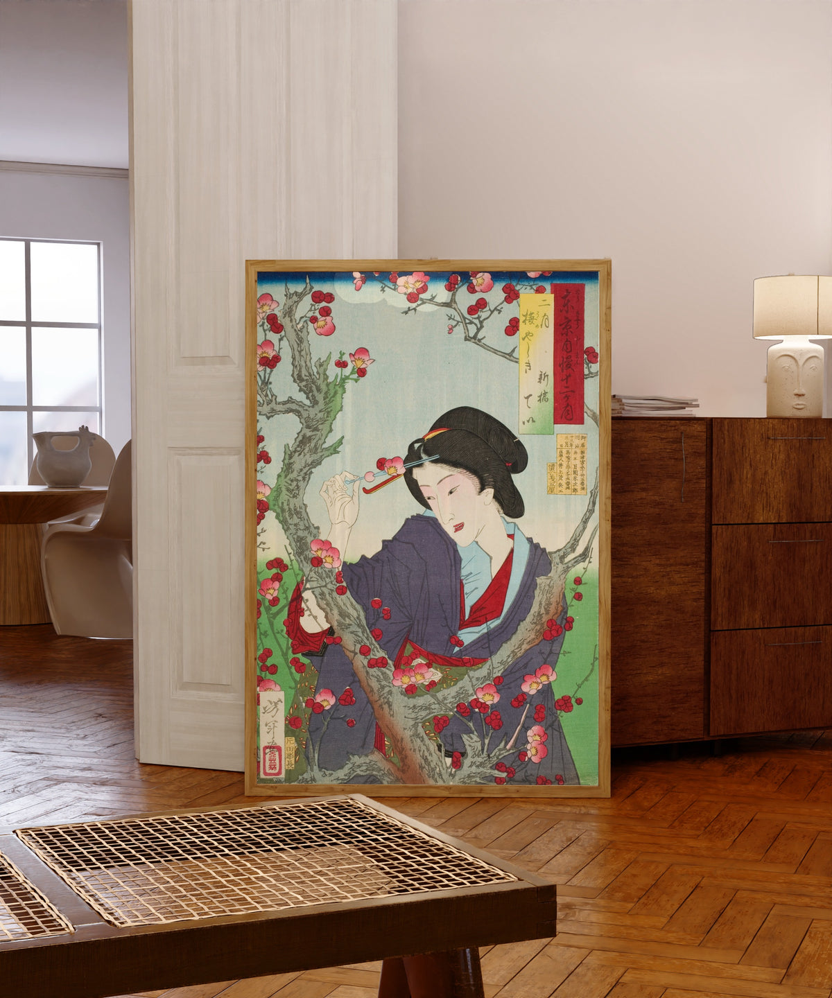 Framed art print of Second Month; Tei of Shinbashi by a Plum Tree at… by Tsukioka Yoshitoshi, in a light wood frame leaning in a warm room with a parquet floor