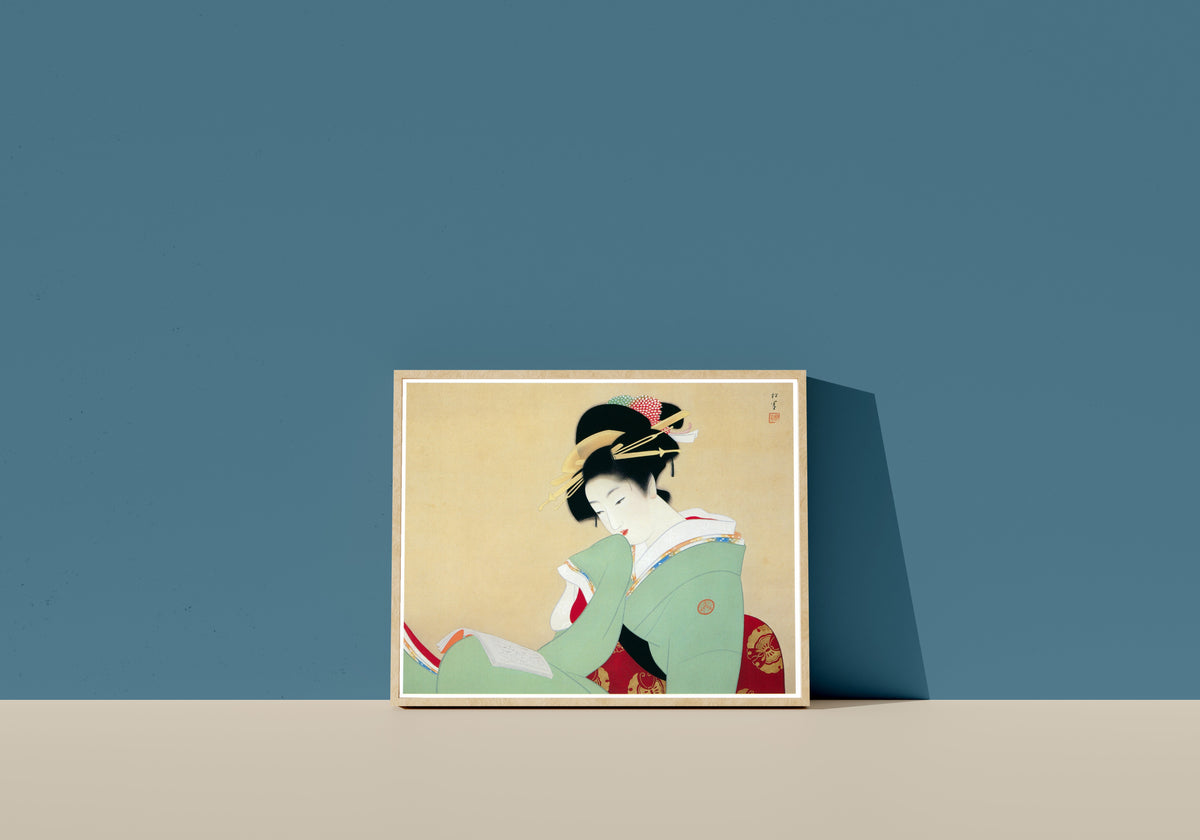 Framed art print of Beautiful Woman Reading a Book by Uemura Shōen, in a light wood frame leaning on a blue wall