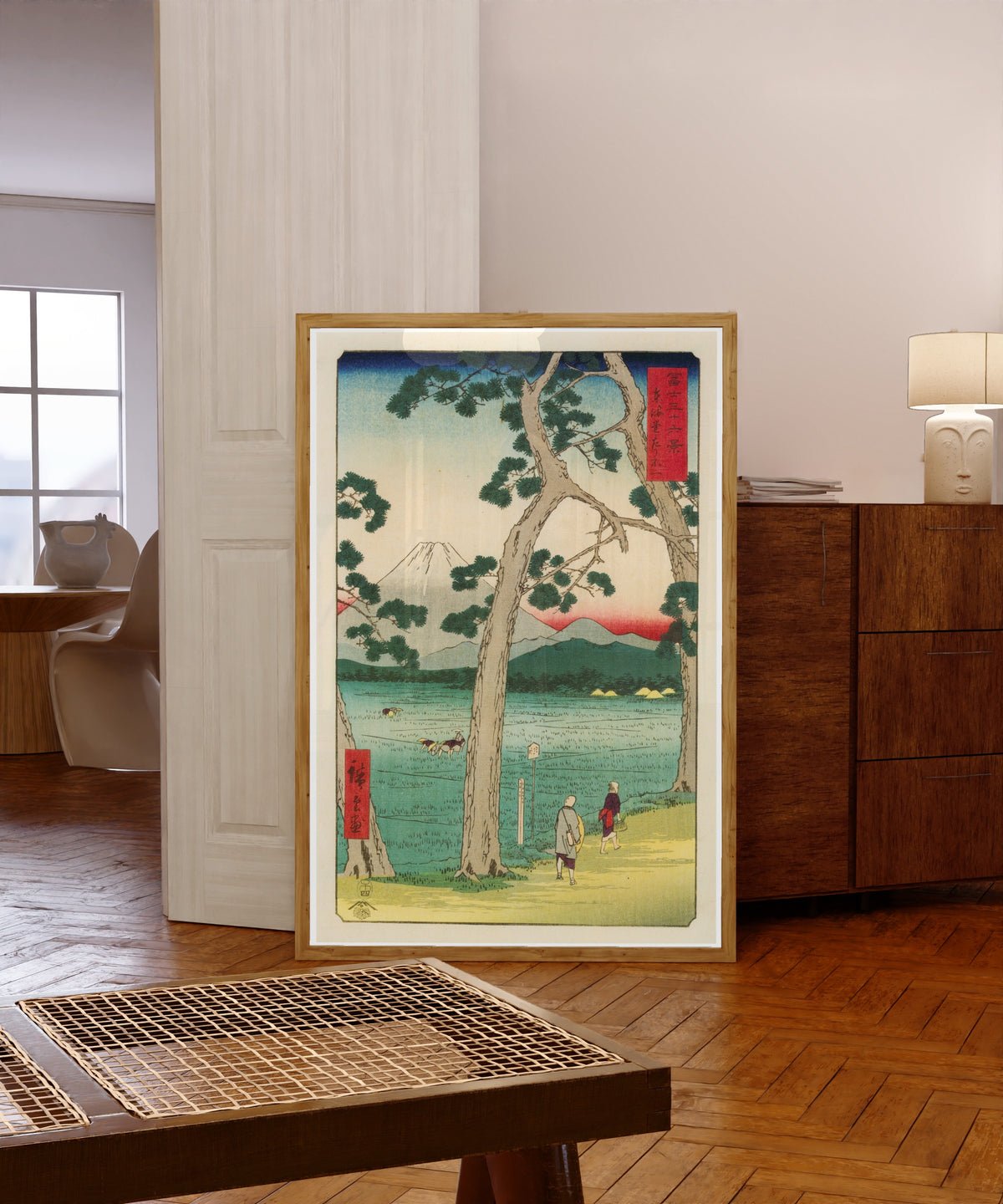 Framed art print of Fuji on the left of the Tōkaidō Road by Utagawa Hiroshige, in a light wood frame leaning in a warm room with a parquet floor