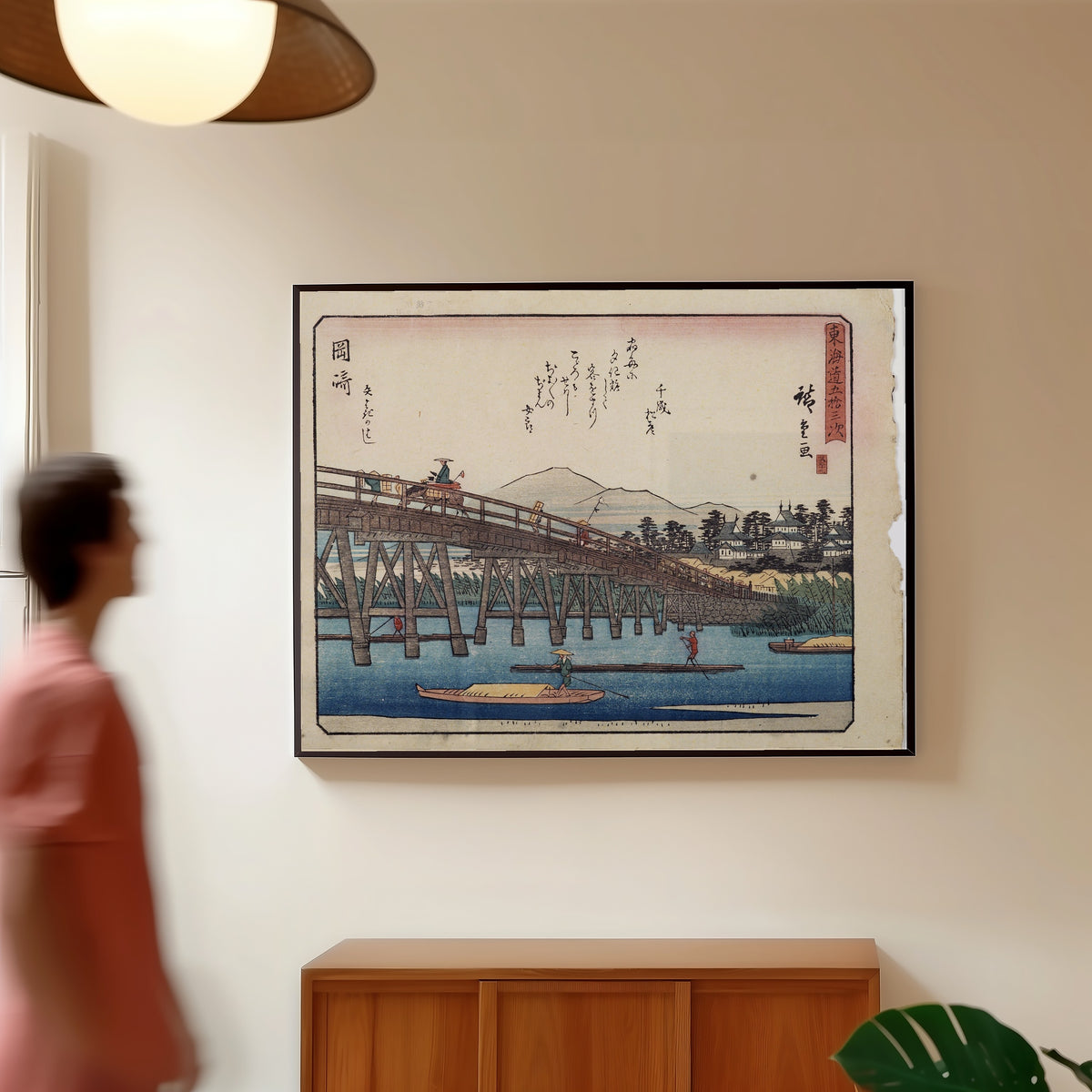 Framed art print of Kyōka Tōkaidō: Okazaki, Yahagi Bridge by Utagawa Hiroshige, in a slim black frame on a warm wall in a sunlit room