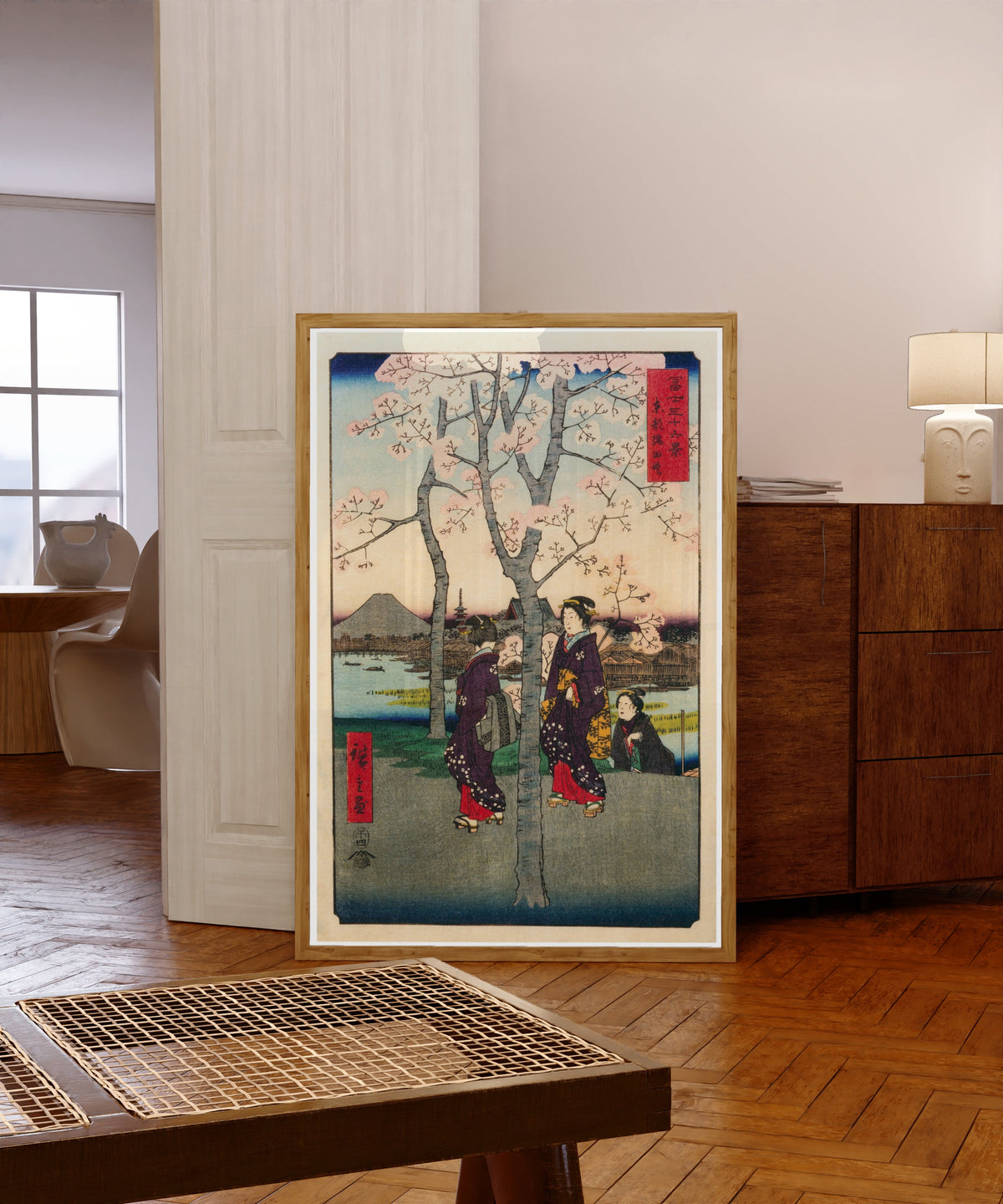 Framed art print of The Sumida Embankment in the Eastern Capital by Utagawa Hiroshige, in a light wood frame leaning in a warm room with a parquet floor
