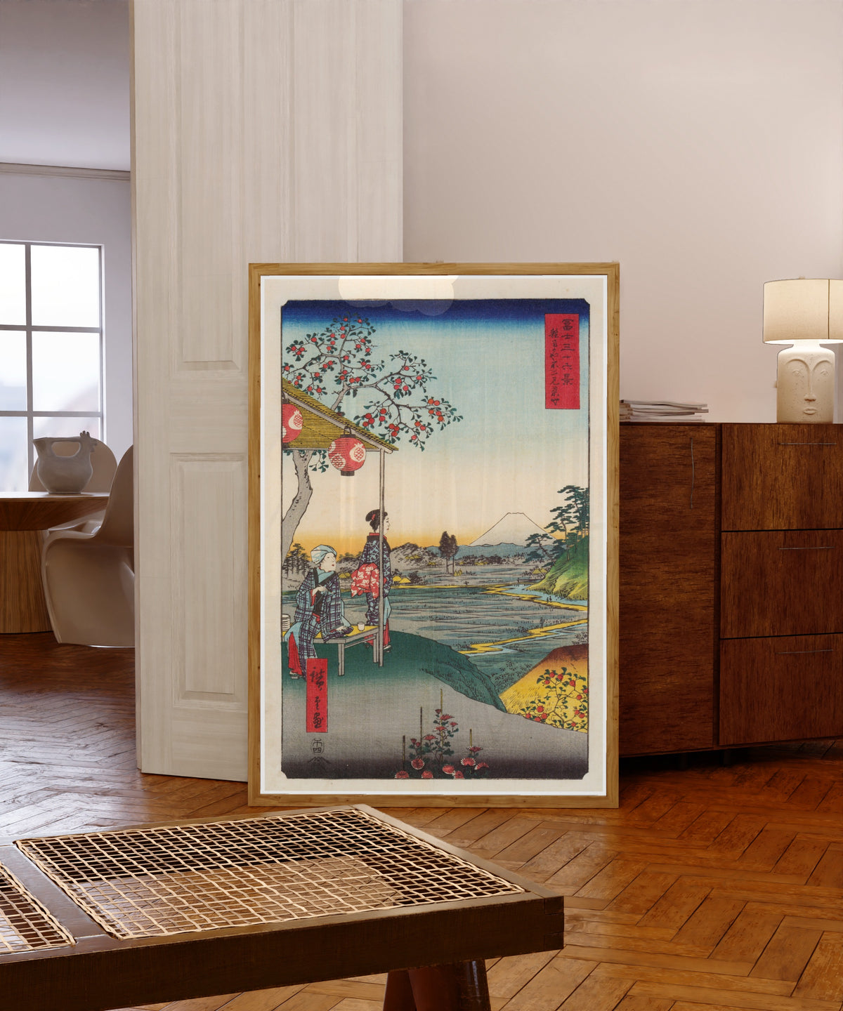 Framed art print of The Teahouse with the View of Mt. Fuji at Zōshigaya by Utagawa Hiroshige, in a light wood frame leaning in a warm room with a parquet floor
