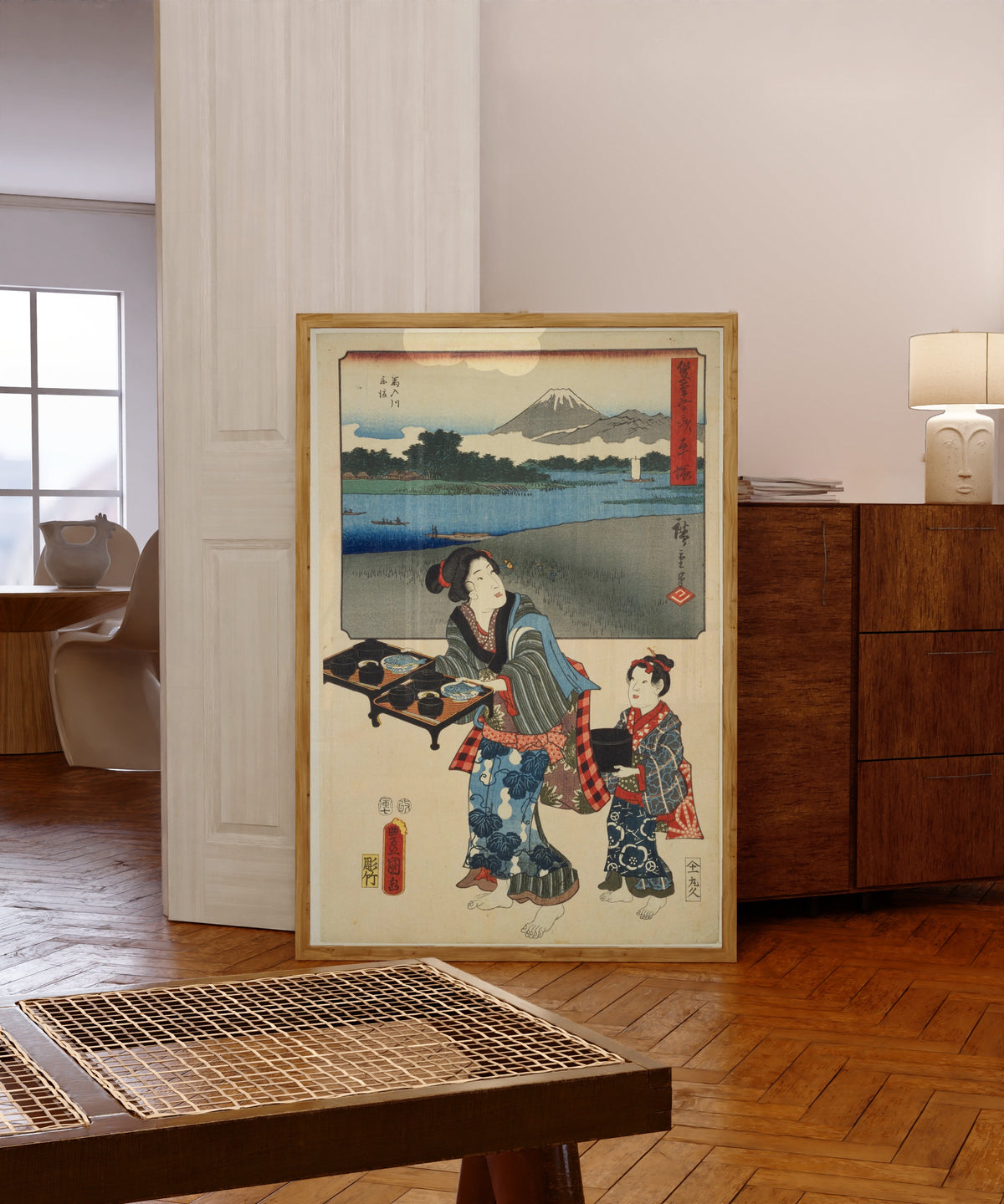 Framed art print of Fifty-three Stations by Two… by Utagawa Hiroshige & Utagawa Kunisada, in a light wood frame leaning in a warm room with a parquet floor