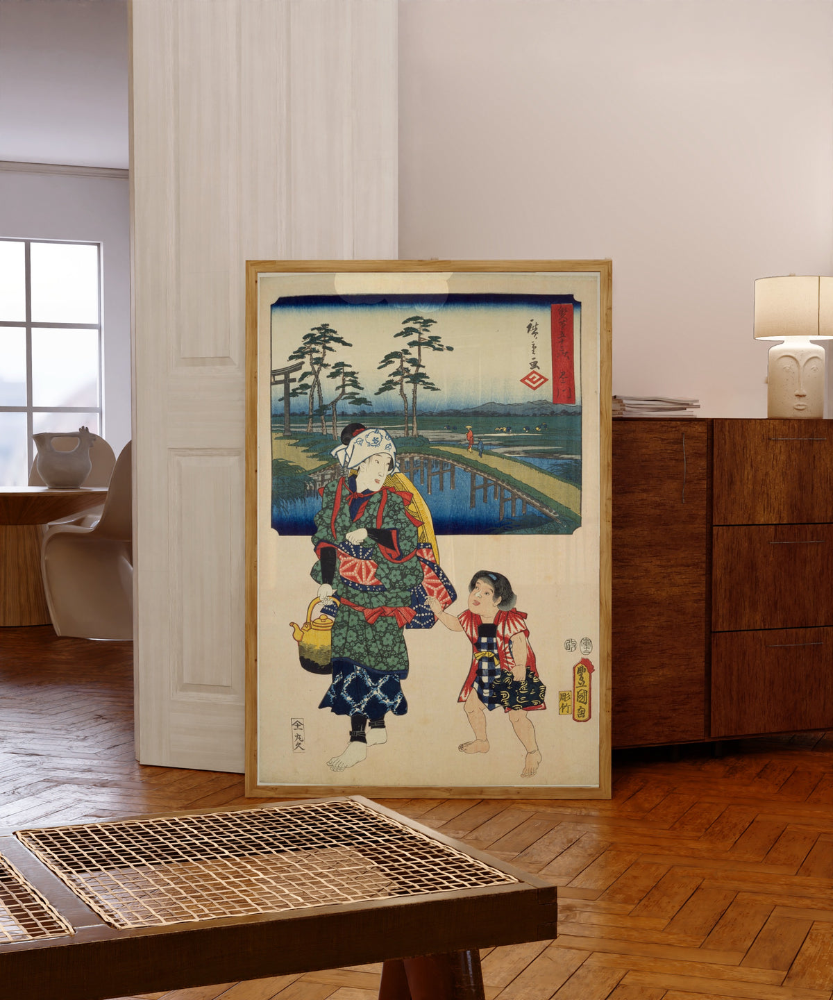 Framed art print of Fifty-three Stations by Two… by Utagawa Hiroshige & Utagawa Kunisada, in a light wood frame leaning in a warm room with a parquet floor