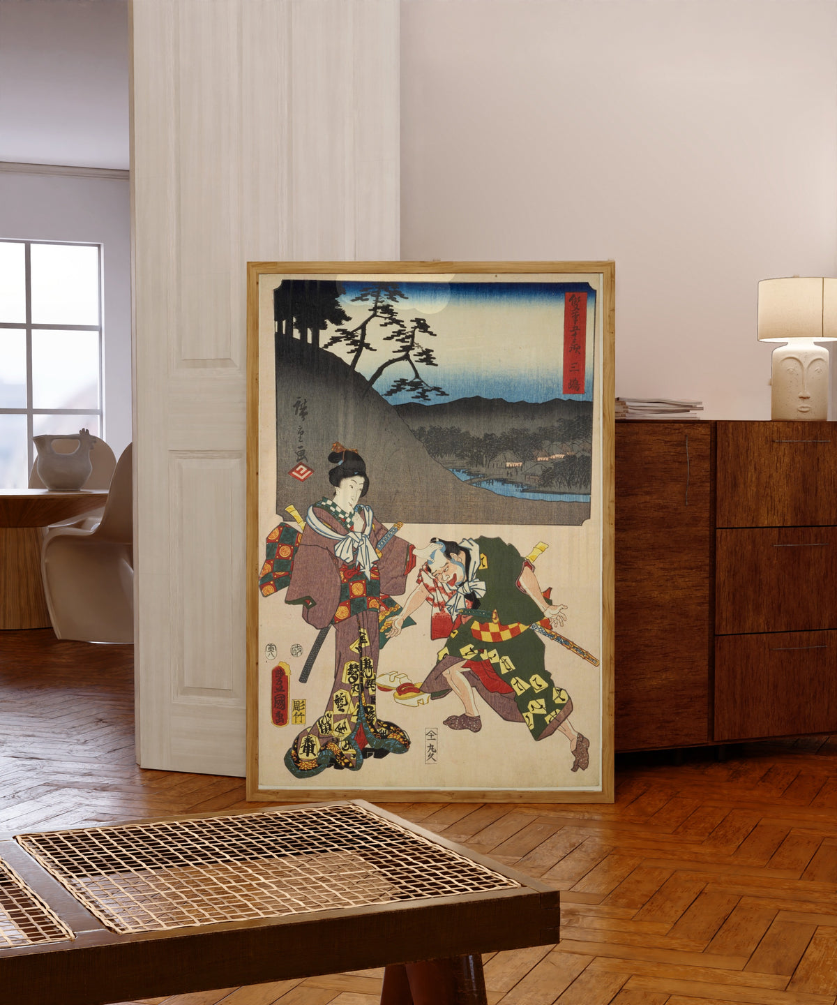 Framed art print of Fifty-three Stations by Two… by Utagawa Hiroshige & Utagawa Kunisada, in a light wood frame leaning in a warm room with a parquet floor