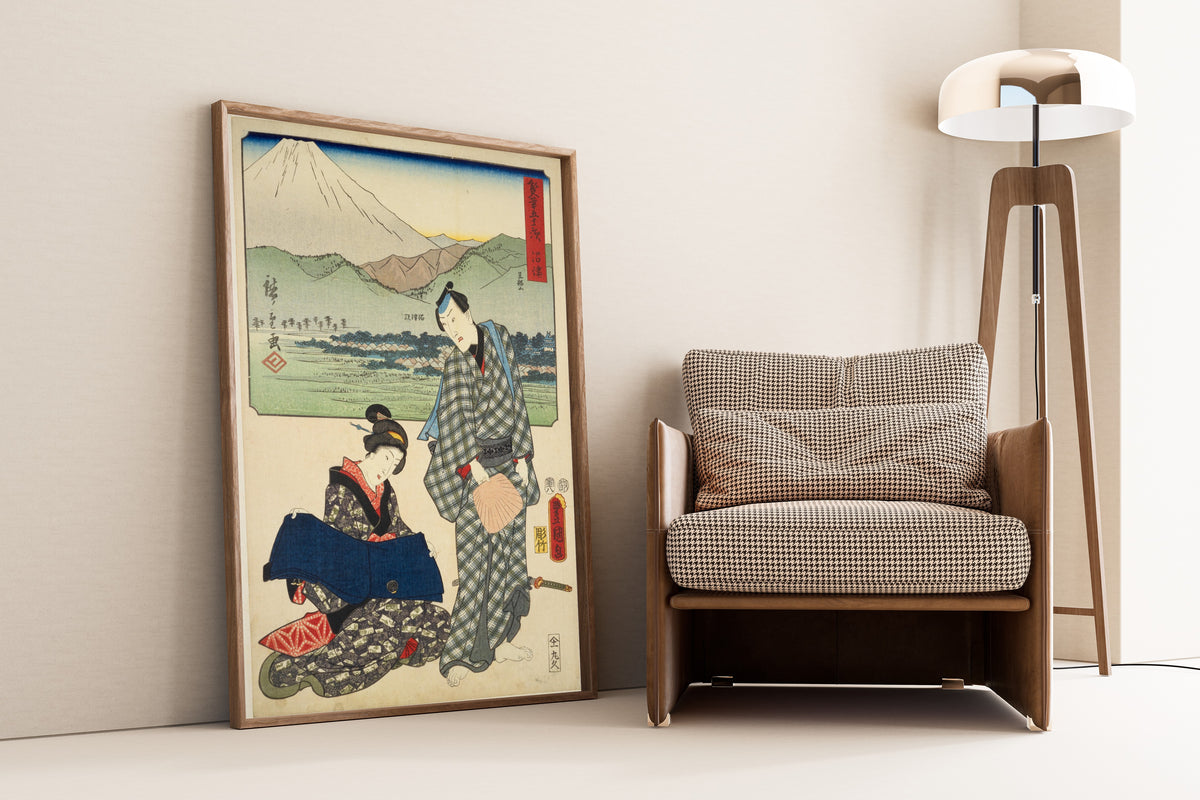 Fifty-three Stations by Two Brushes: Numazu by Utagawa Hiroshige & Utagawa Kunisada — framed and leaning against a wall beside an armchair and a floor lamp