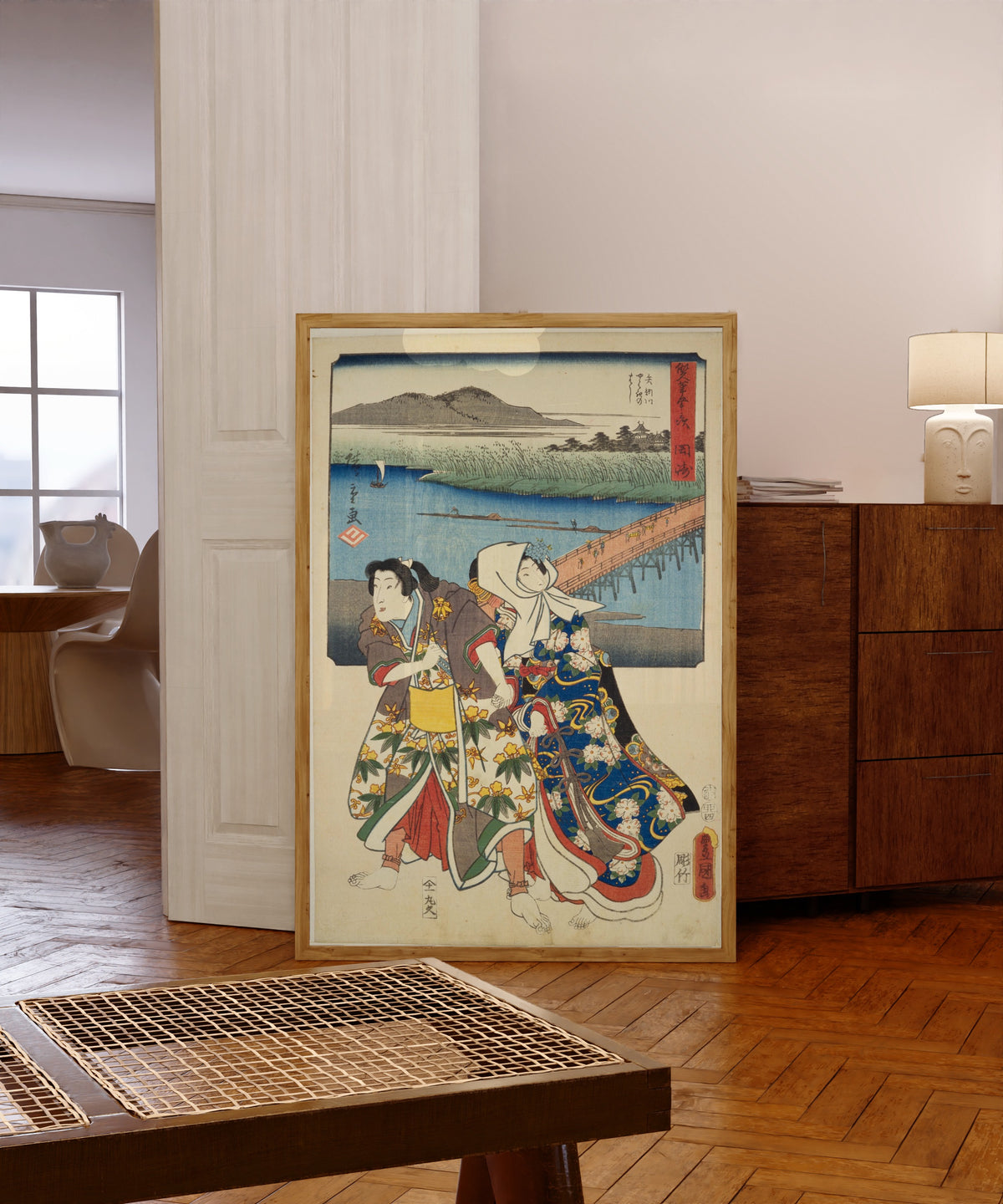Framed art print of Fifty-three Stations by Two… by Utagawa Hiroshige & Utagawa Kunisada, in a light wood frame leaning in a warm room with a parquet floor