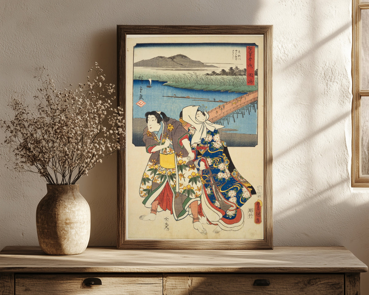 Framed art print of Fifty-three Stations by Two… by Utagawa Hiroshige & Utagawa Kunisada, in a dark wood frame leaning on a rustic console beside dried flowers