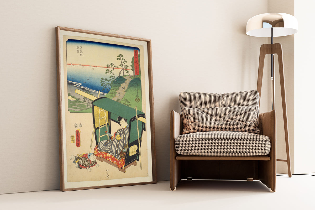 Fifty-three Stations by Two Brushes: Shirasuka by Utagawa Hiroshige & Utagawa Kunisada — framed and leaning against a wall beside an armchair and a floor lamp
