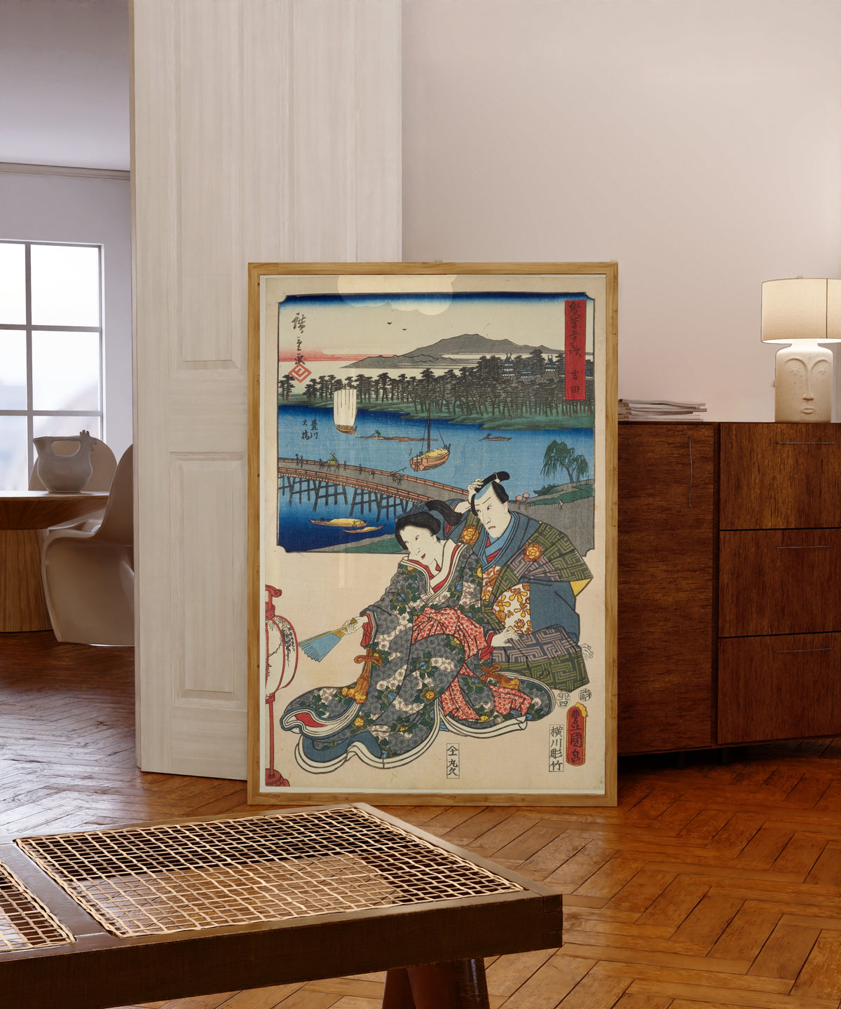 Framed art print of Fifty-three Stations by Two… by Utagawa Hiroshige & Utagawa Kunisada, in a light wood frame leaning in a warm room with a parquet floor