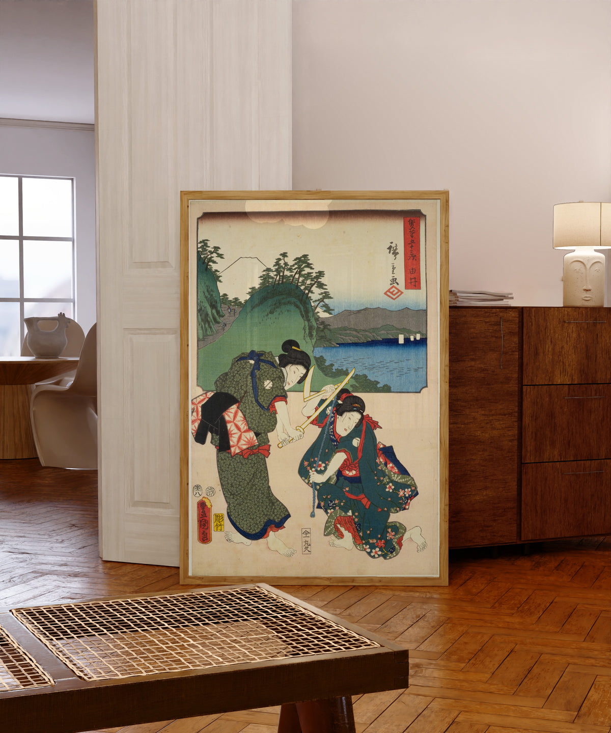Framed art print of Fifty-three Stations by Two… by Utagawa Hiroshige & Utagawa Kunisada, in a light wood frame leaning in a warm room with a parquet floor