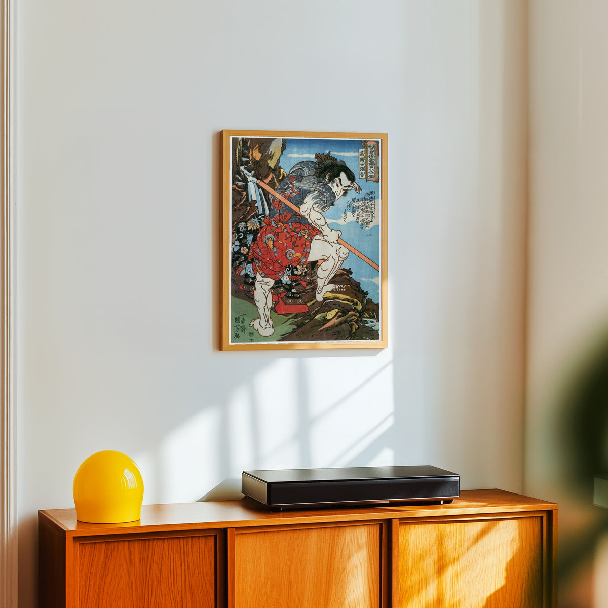 Framed art print of 108 Heroes of the Suikoden: Saienshi Chōsei by Utagawa Kuniyoshi, in a light wood frame on a white wall above an orange sideboard