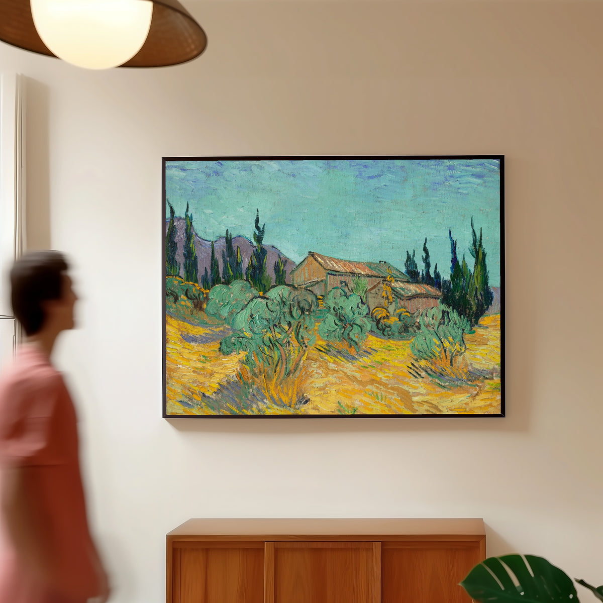 Framed art print of Huts surrounded by Olive Trees and Cypresses by Vincent van Gogh, in a slim black frame on a warm wall in a sunlit room