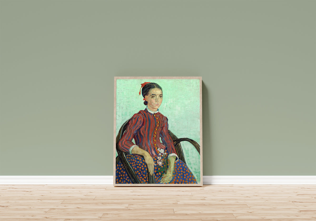 Framed art print of La Mousmé by Vincent van Gogh, in a light wood frame leaning on a sage green wall above a wooden floor