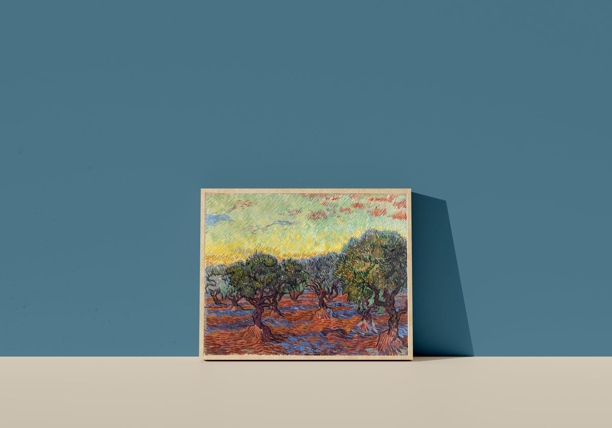 Framed art print of Olive Grove, Saint-Rémy by Vincent van Gogh, in a light wood frame leaning on a blue wall