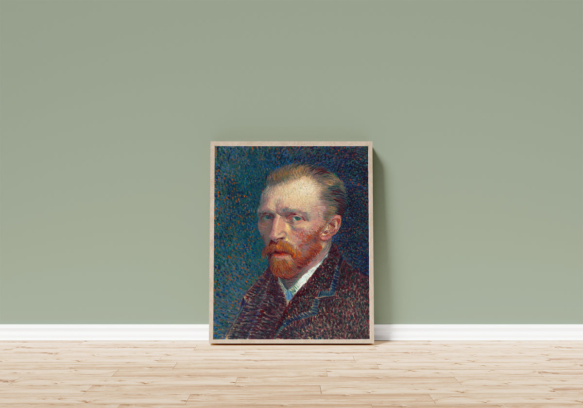 Framed art print of Self-Portrait by Vincent van Gogh, in a light wood frame leaning on a sage green wall above a wooden floor